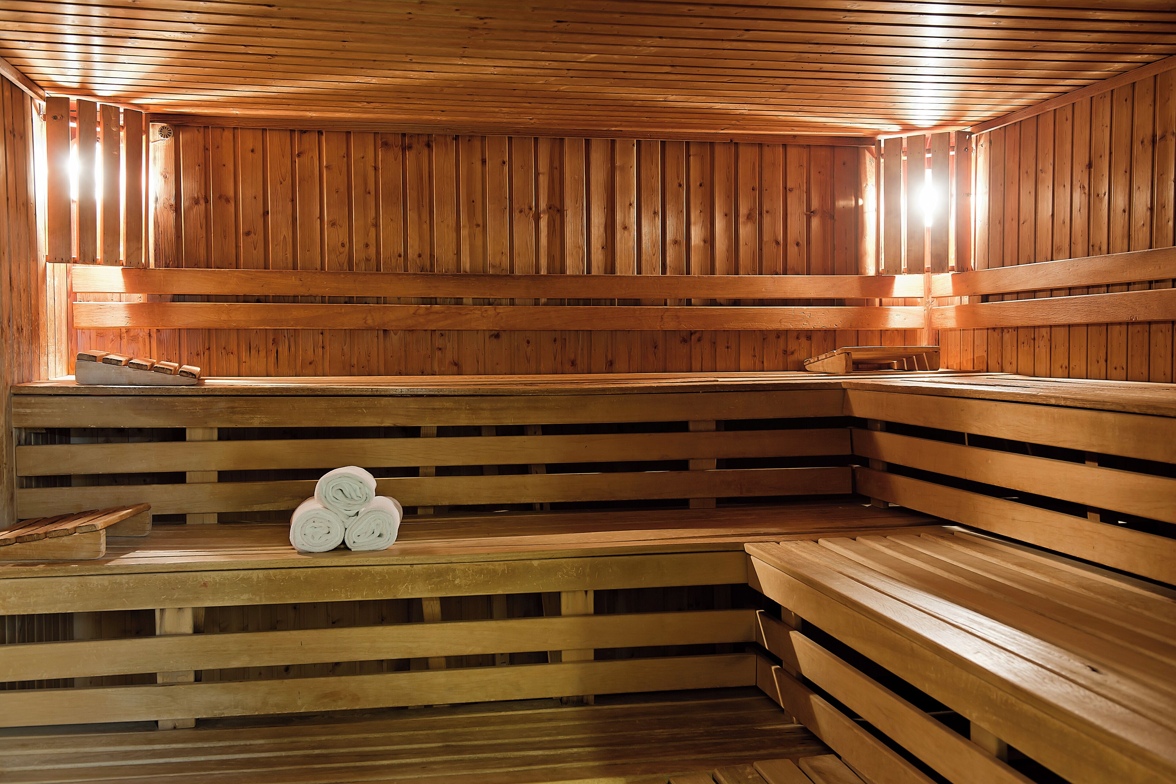A sauna with wooden benches and benches, and a bench with towels.