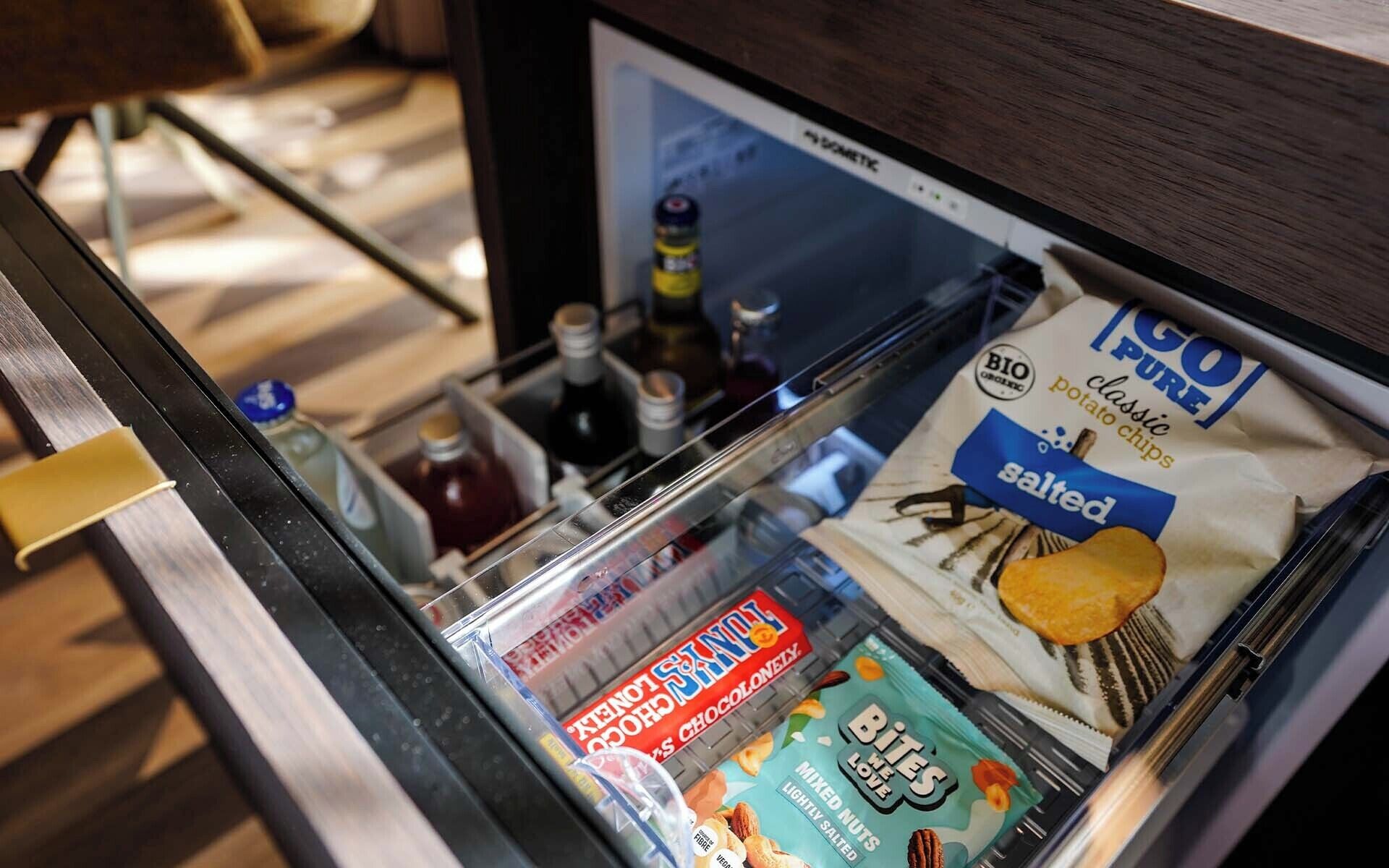 Een hotelminibar gevuld met diverse snacks en drankjes.