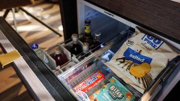 Een hotelminibar gevuld met diverse snacks en drankjes.