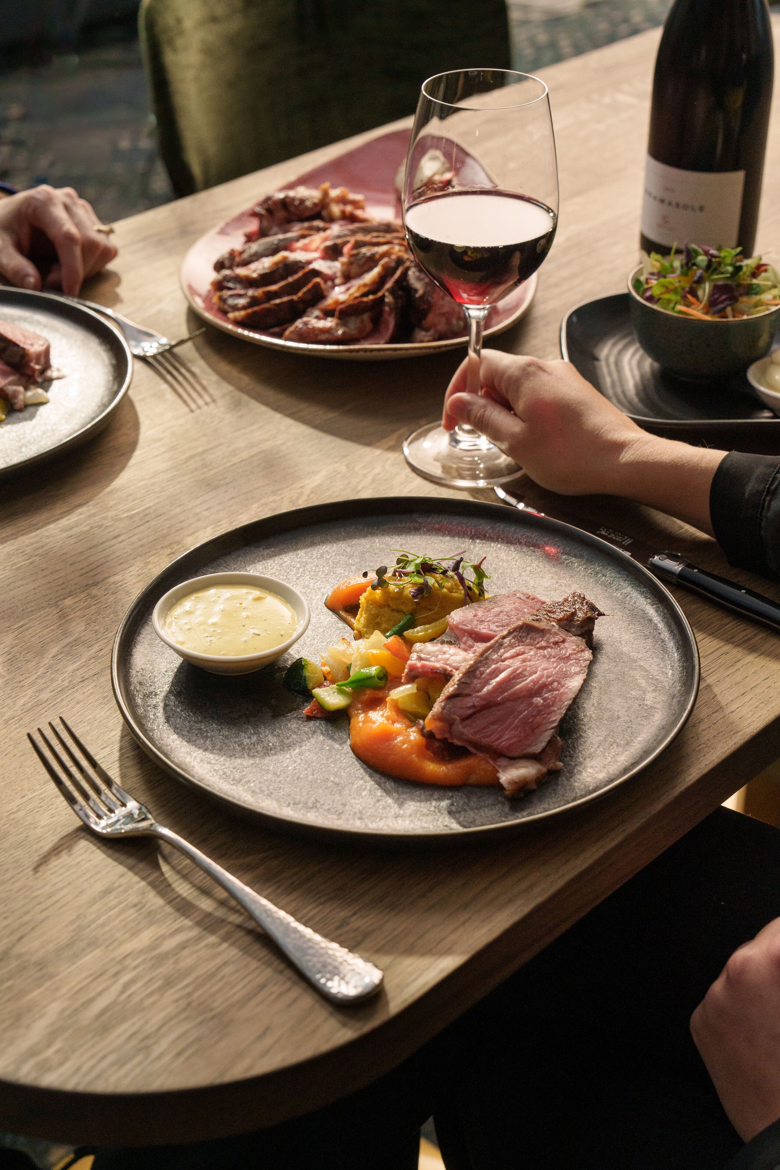 Una mesa de comedor con platos de comida, una copa de vino y una botella.