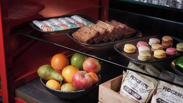 A bakery display with pastries, macarons, and a bowl of fruits.