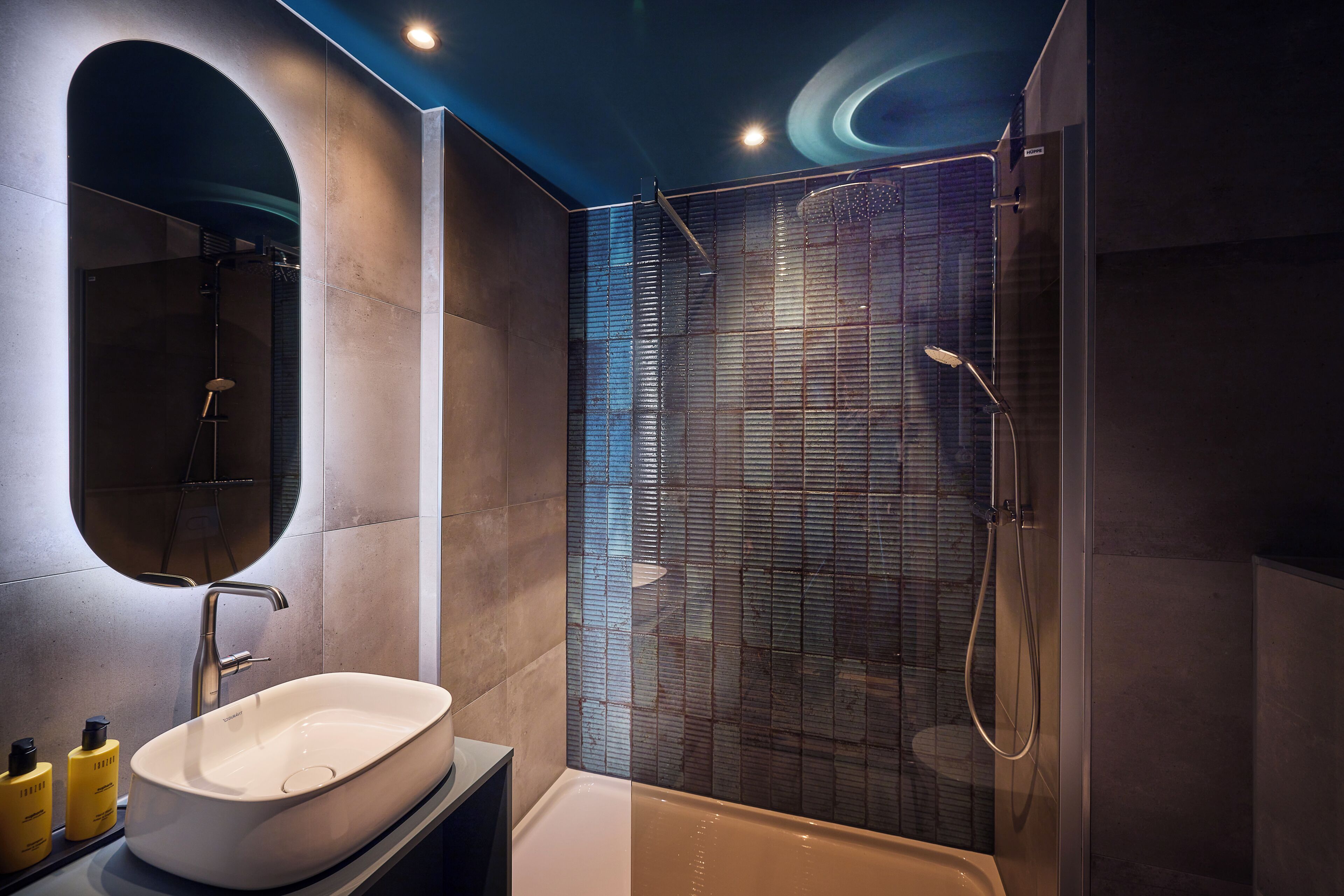A modern bathroom with a large mirror, a bathtub, and a shower enclosure.