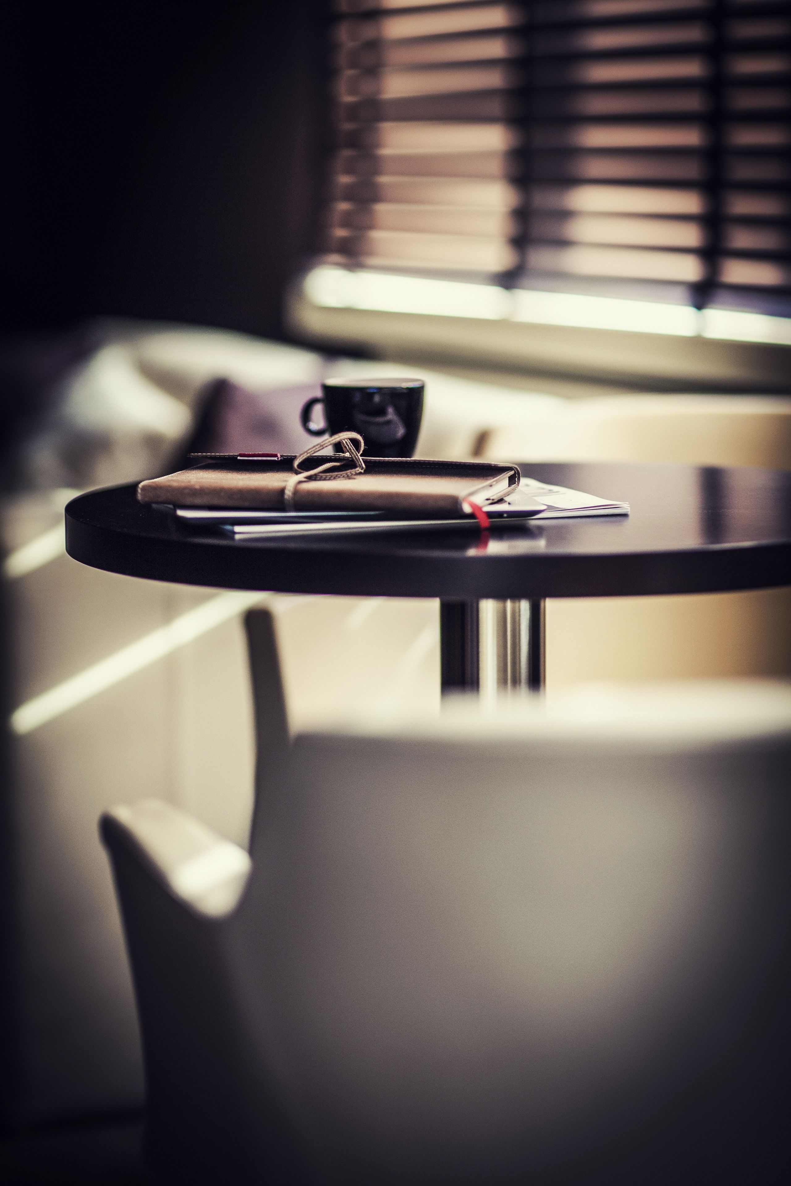 A round table with a notebook, pen, and a cup.