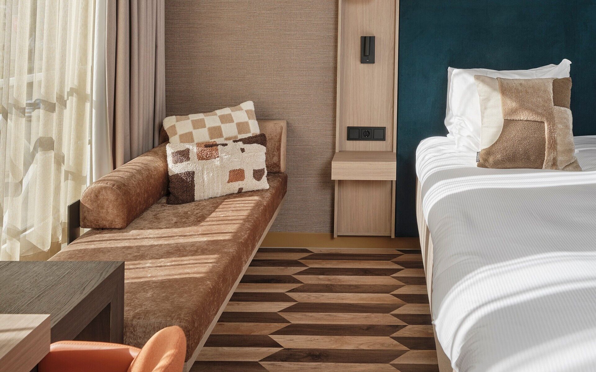 Una habitación de hotel con sofá cama, mesita de noche, escritorio pequeño y cama con almohadas.