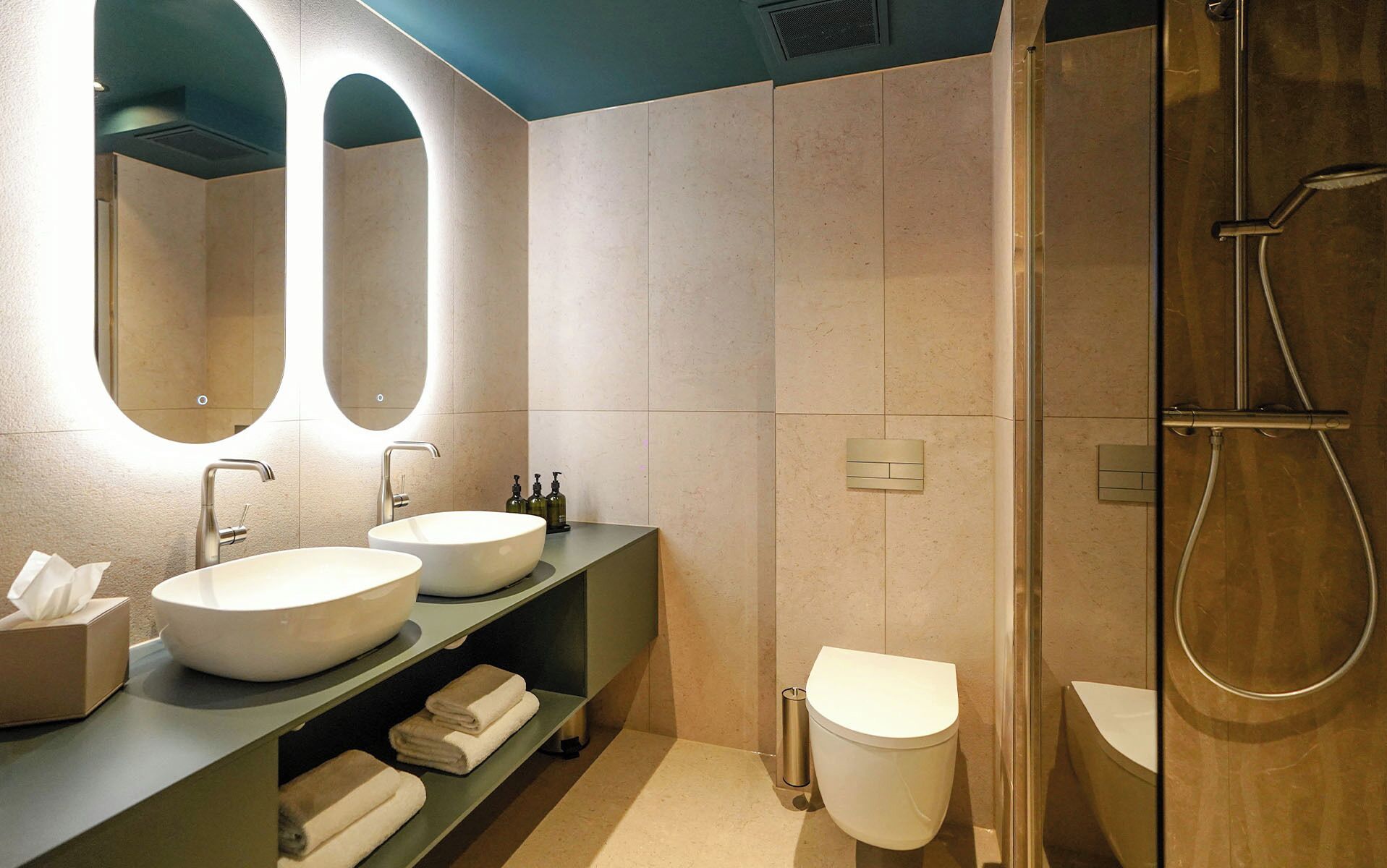 Un baño moderno con dos lavamanos, un inodoro y una ducha.