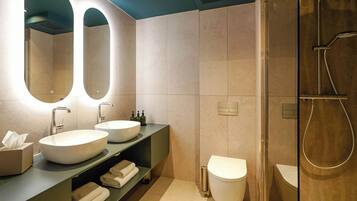 A modern bathroom with two sinks, a toilet, and a shower.