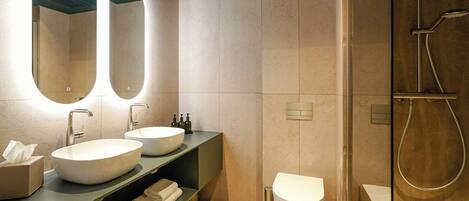 Un baño moderno con dos lavamanos, un inodoro y una ducha.