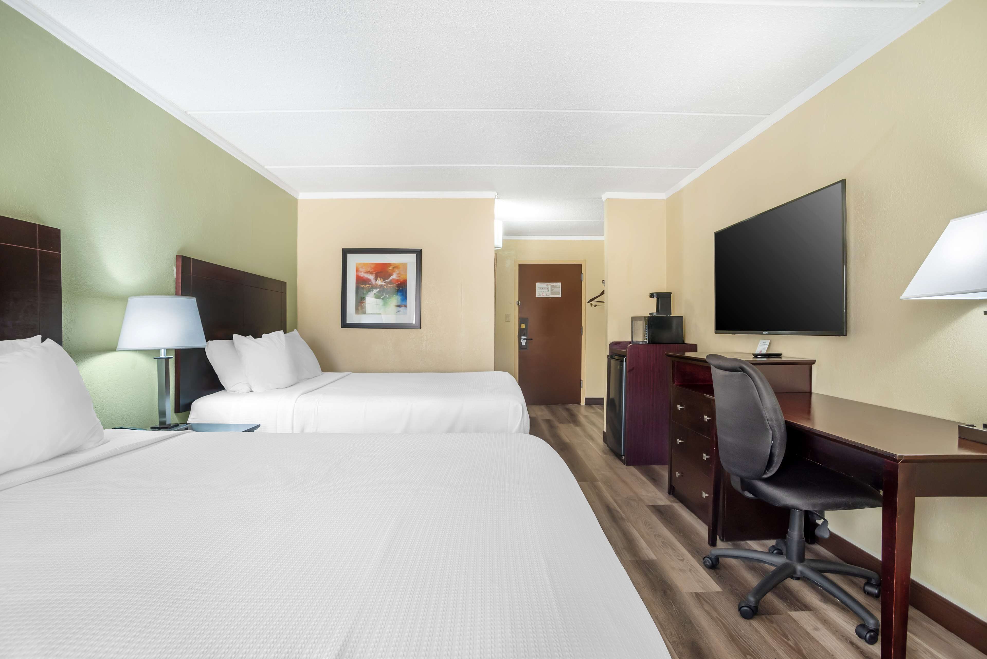Een hotelkamer met twee bedden, een bureau, een stoel, een televisie en een bureaulamp.