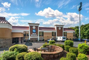Un hotel Best Western con estacionamiento, zona de estar al aire libre y un cielo azul despejado.