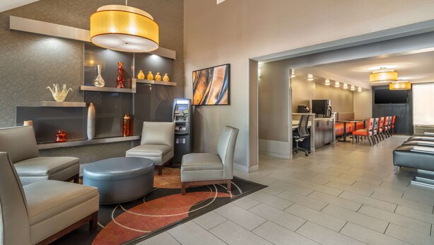 A modern hotel lobby with seating areas, a reception desk, and a large screen. - Best Western Charlotte-Gastonia (Gastonia)