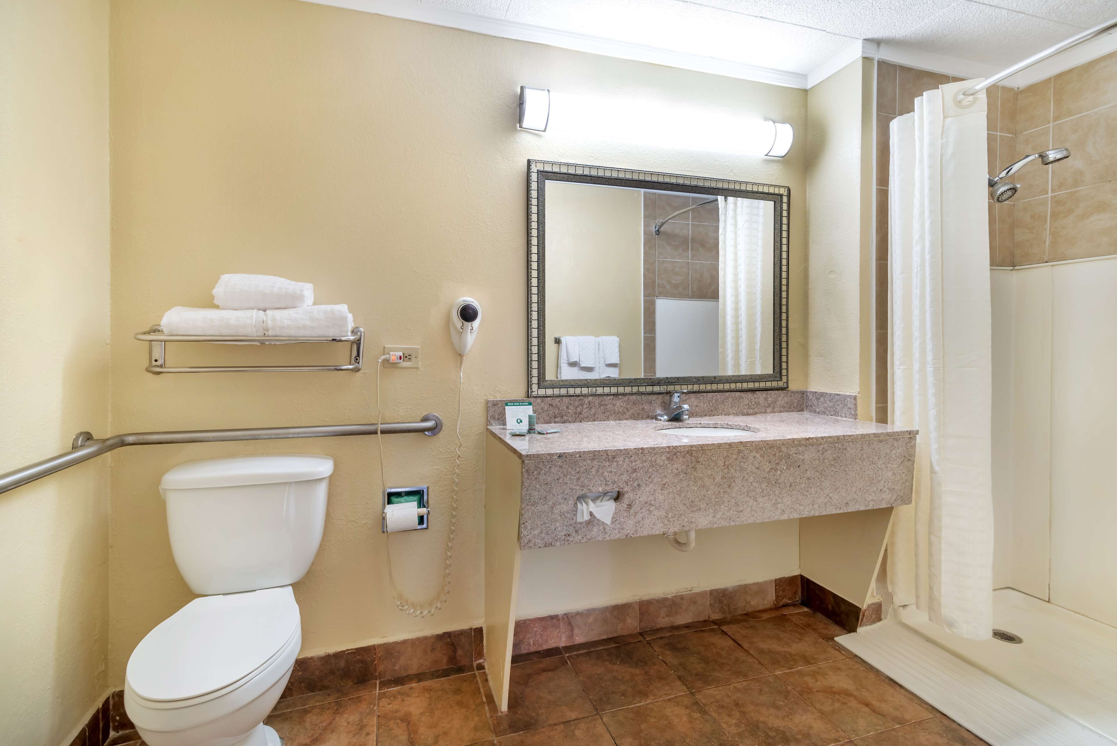 A bathroom with a toilet, sink, mirror, towel rack, and shower.