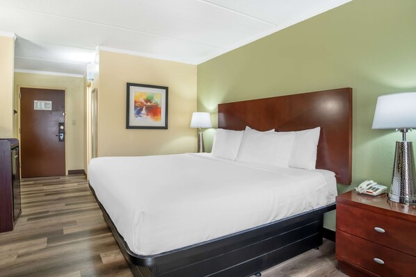 A hotel room with a large bed, a wooden headboard, a bedside table with a lamp, and a phone. - Best Western Charlotte-Gastonia (Gastonia)