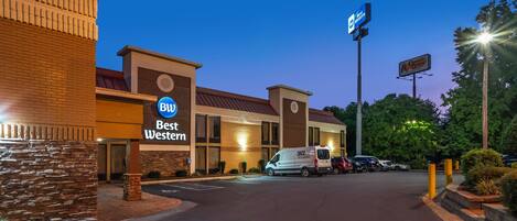 A Best Western hotel with a brick facade, a parking lot, and a van parked in front.