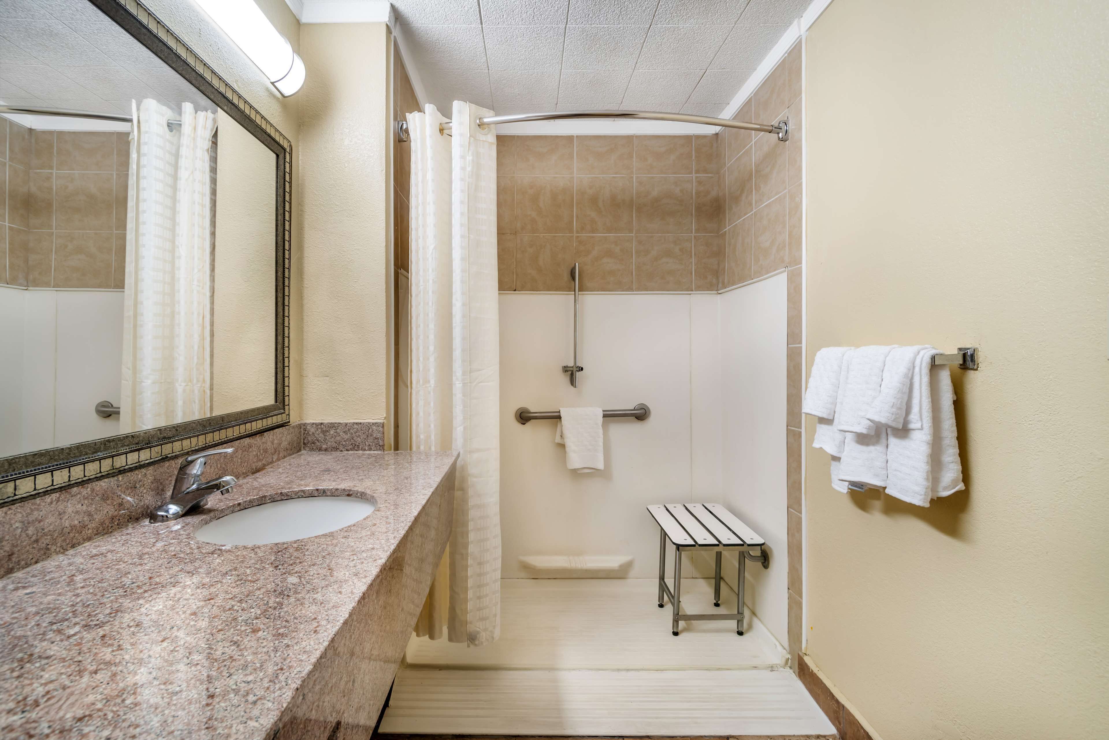 A bathroom with a granite sink, a mirror, a shower with a glass door, and a towel rack.