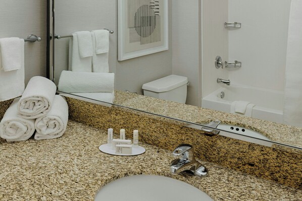 A bathroom with a granite countertop, a sink, a toilet, a shower, and a mirror. - Courtyard by Marriott Springfield Downtown (Springfield)