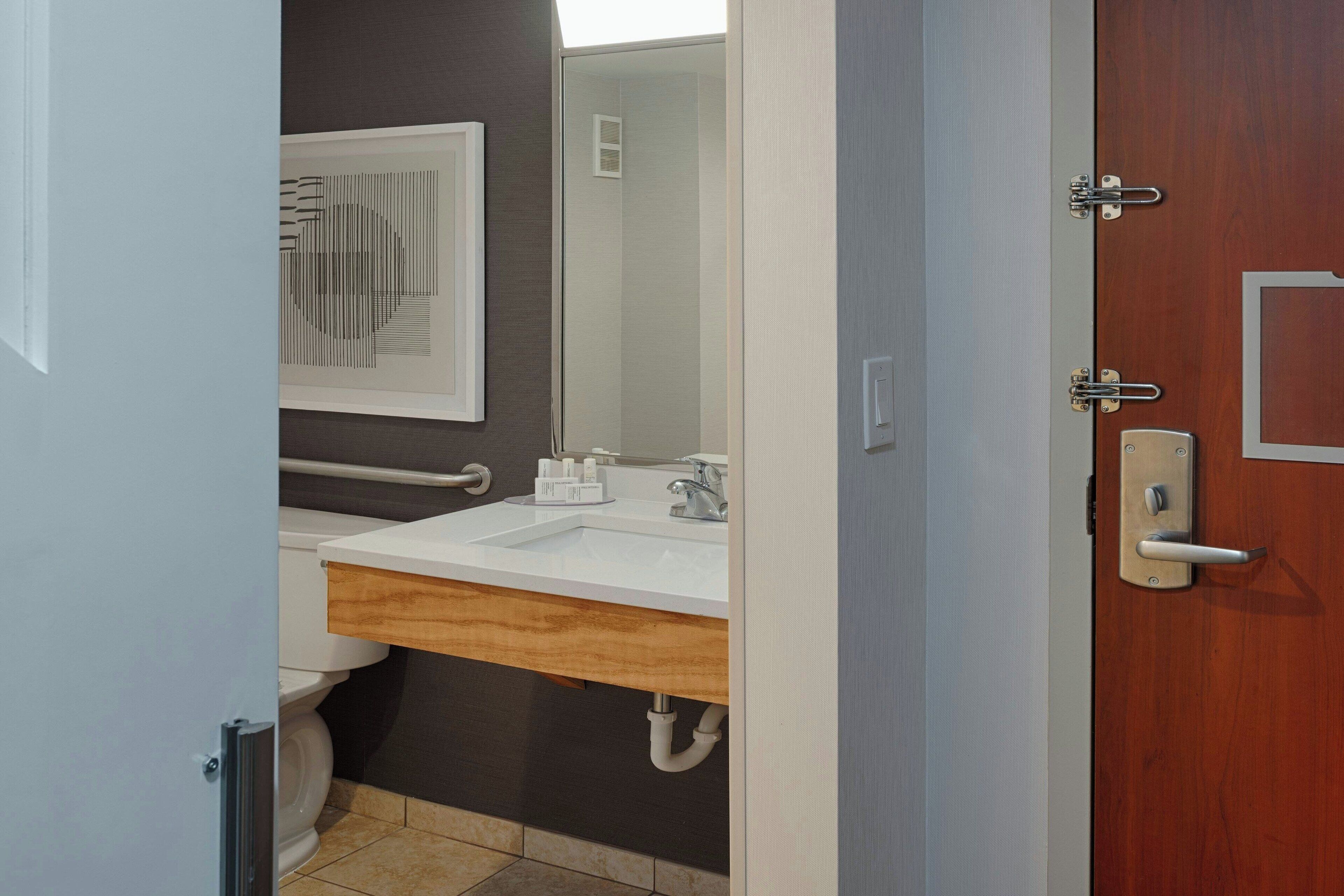 A modern bathroom with a white sink, wooden vanity, and a mirror above the sink.