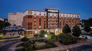 A Courtyard by Marriott hotel with a brick facade, multiple floors, and a well-lit entrance area with outdoor seating. - Courtyard by Marriott Springfield Downtown (Springfield)