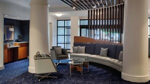 A modern lobby with a curved sofa, a desk, and a chair. - Courtyard by Marriott Springfield Downtown (Springfield)