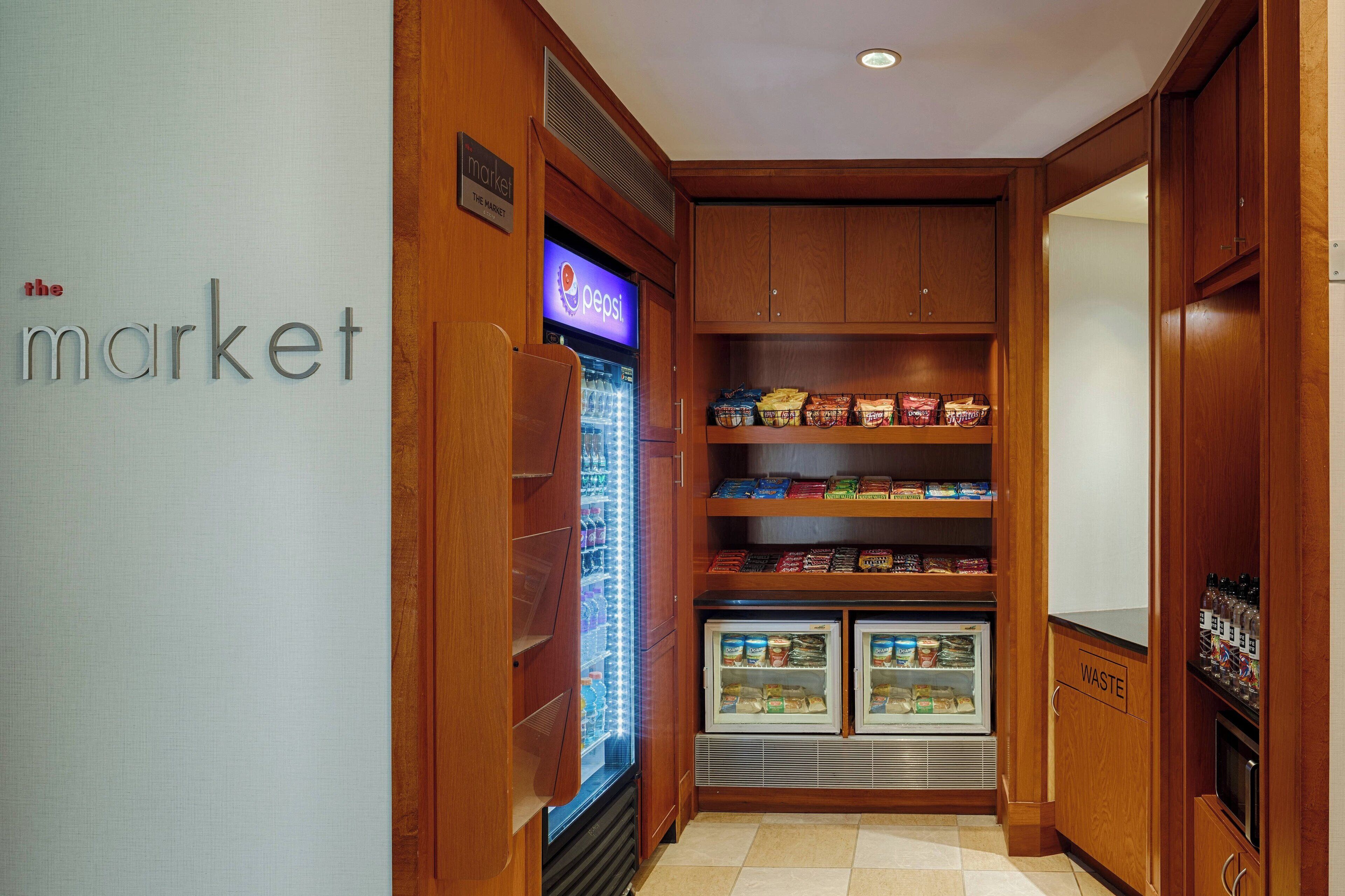 A compact kitchenette with a refrigerator, freezer, and a vending machine.