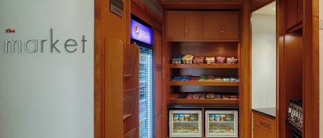 A compact kitchenette with a refrigerator, freezer, and a vending machine.