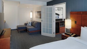 A hotel room with a bed, a desk, a sofa, a microwave, and a door leading to a bathroom. - Courtyard by Marriott Springfield Downtown (Springfield)