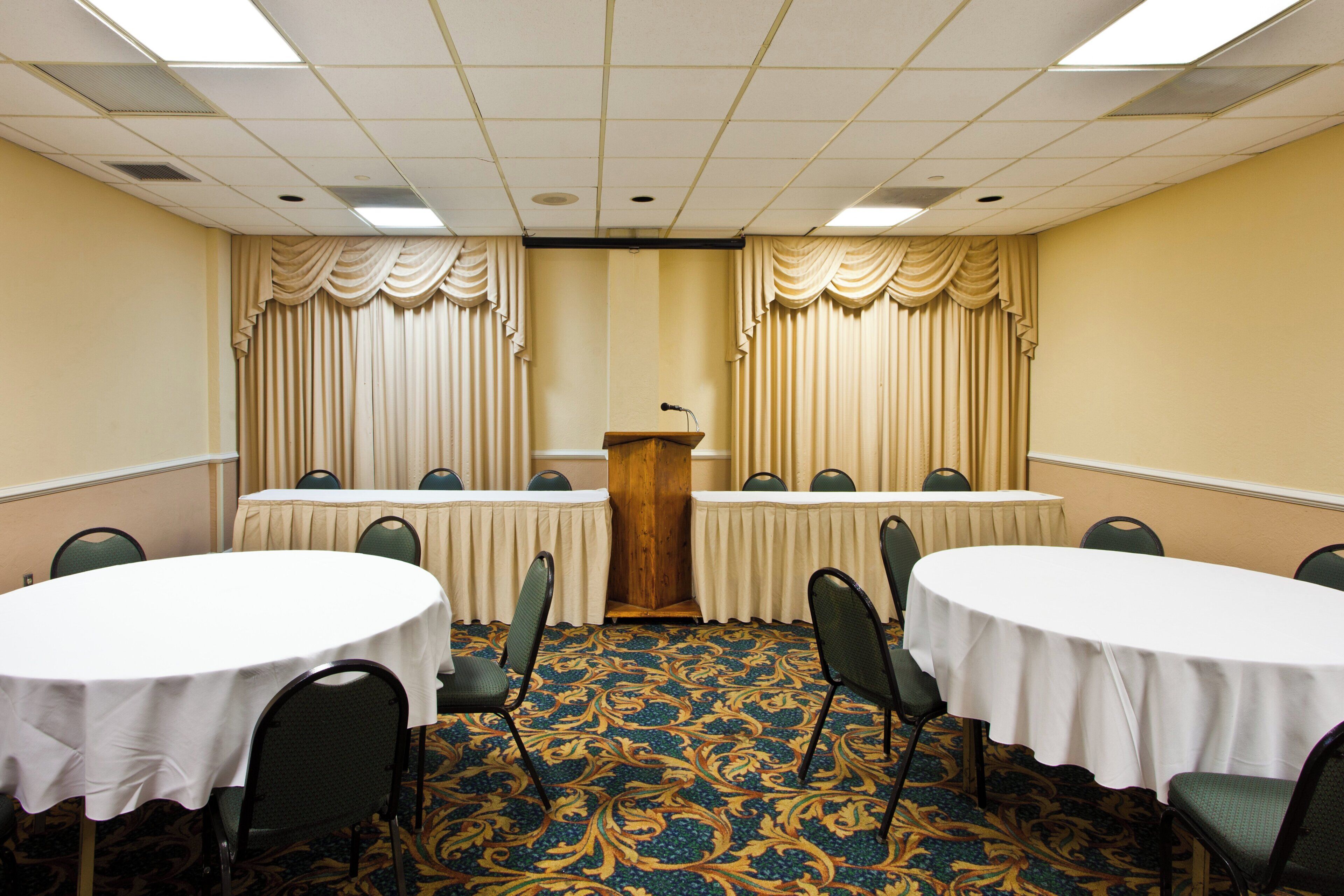 A conference room with a podium, two curtains, and a patterned carpet.
