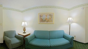 A room with a patterned sofa, a chair, a small table with a lamp, and a framed picture on the wall. - Holiday Inn Port St. Lucie by IHG (Port Saint Lucie)