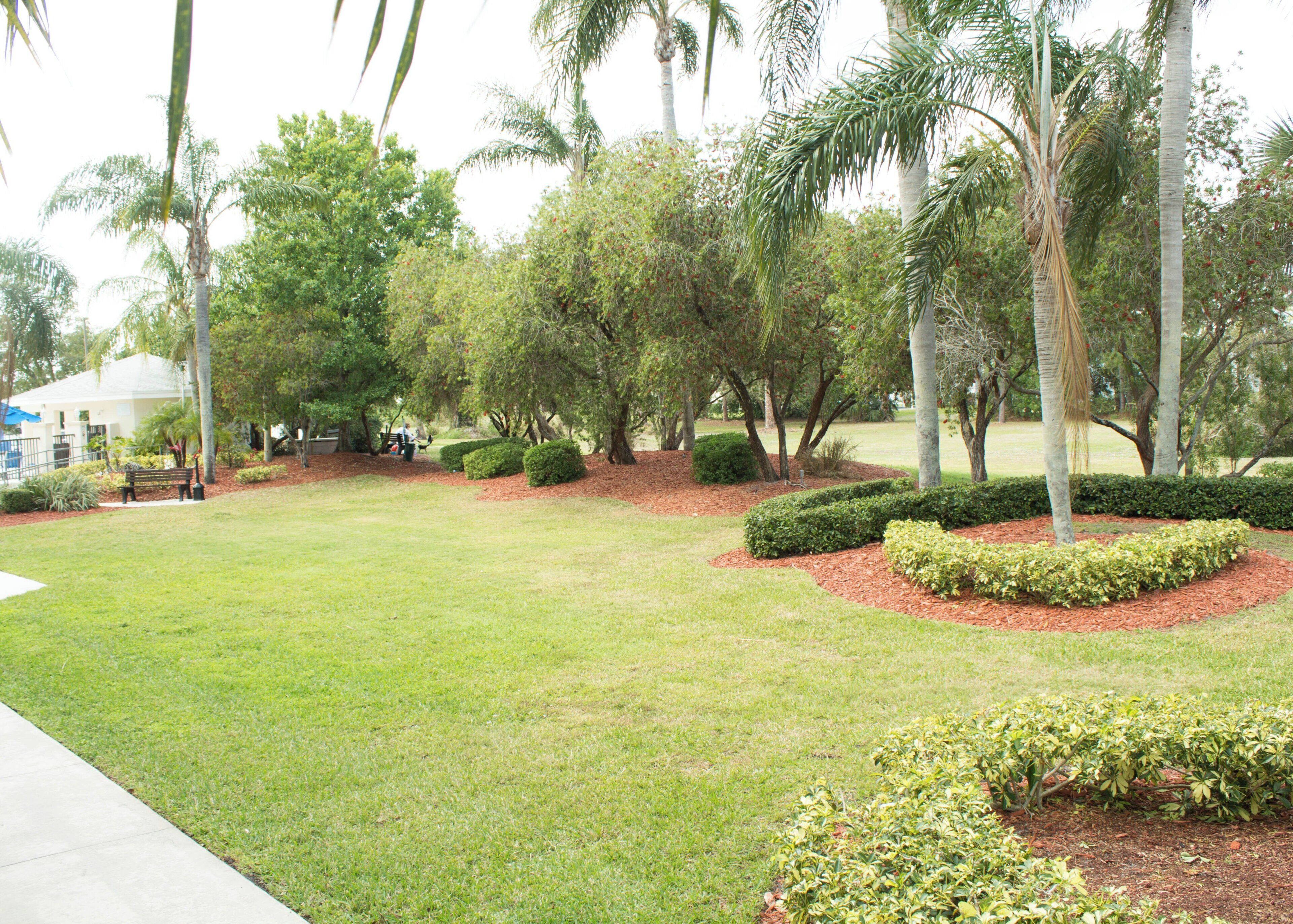A well-maintained grassy area with a bench and a small building in the background.