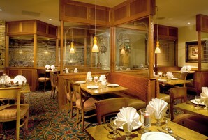 A restaurant interior with wooden furniture, glass partitions, and patterned carpet.
