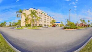 A hotel with a central courtyard, palm trees, and a parking area. - Holiday Inn Port St. Lucie by IHG (Port Saint Lucie)
