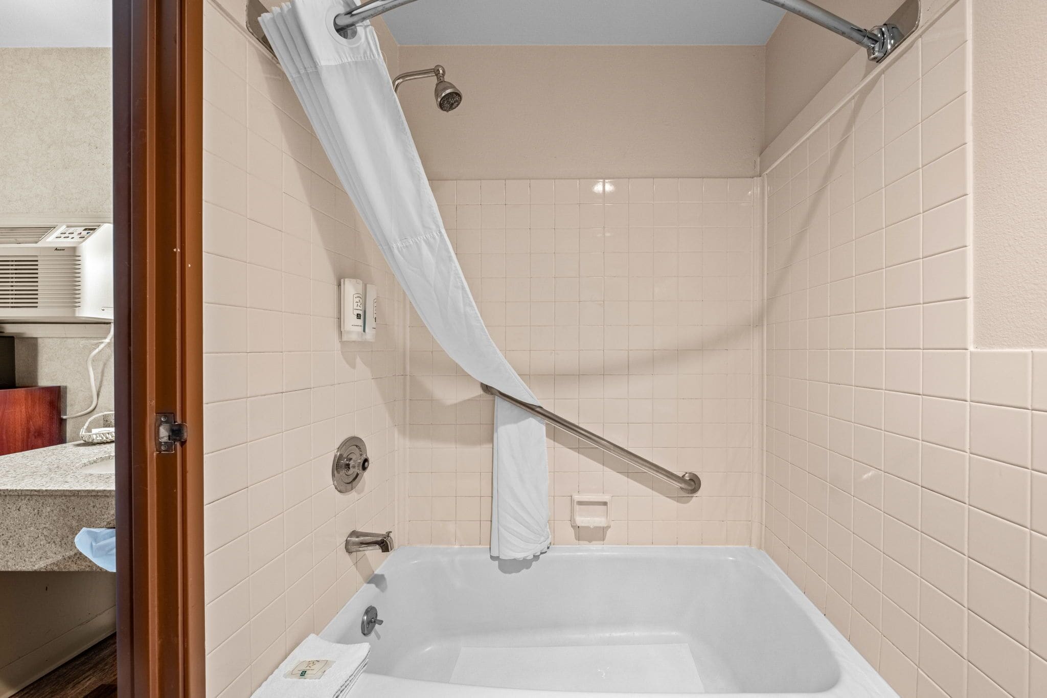 A bathroom with a bathtub, a shower curtain, and a towel rack.