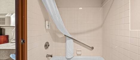 A bathroom with a bathtub, a shower curtain, and a towel rack.