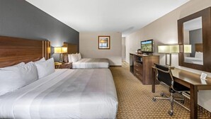 A hotel room with two beds, a desk, a chair, a television, and a mirror.