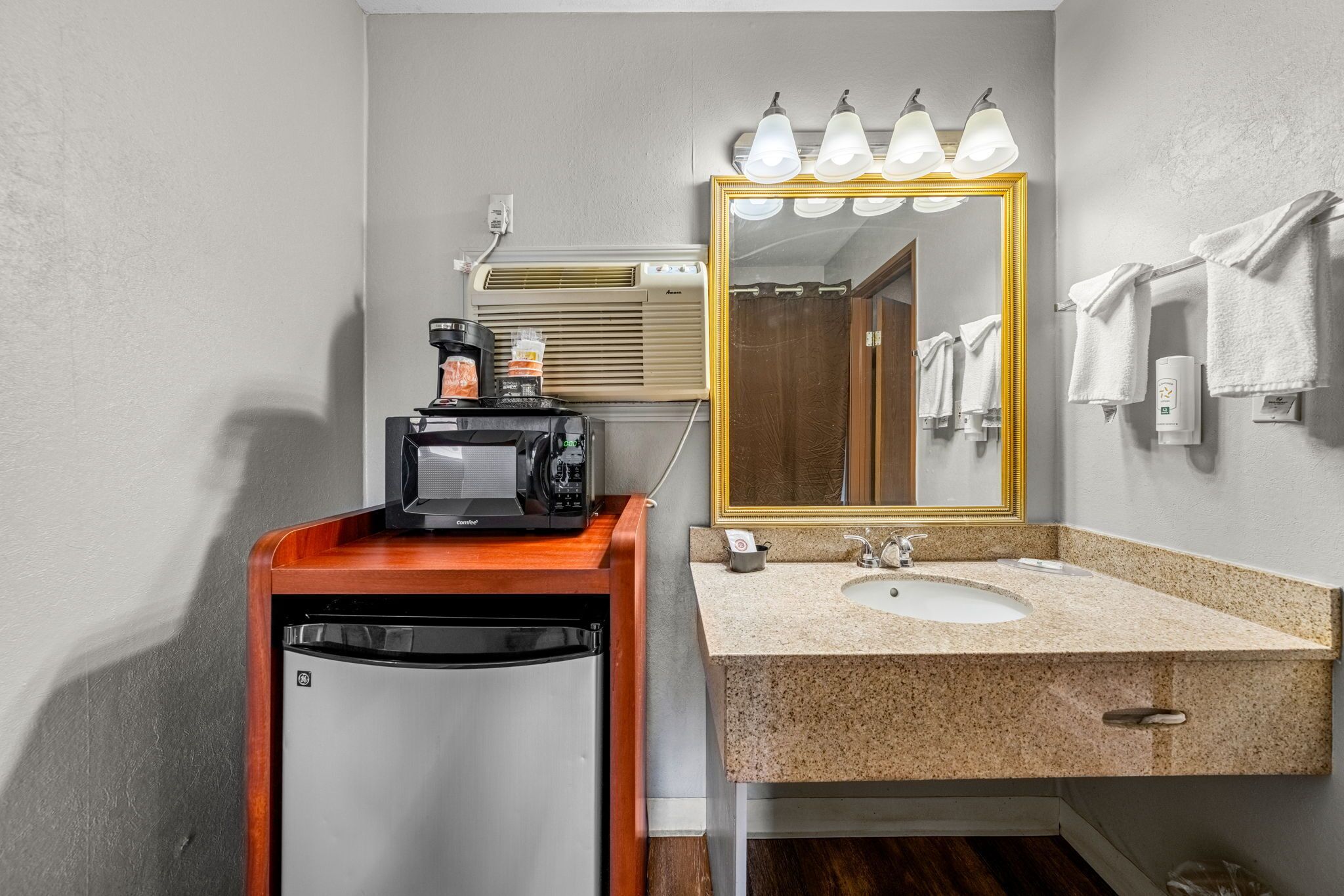 A bathroom with a sink, mirror, towel rack, and a coffee machine.