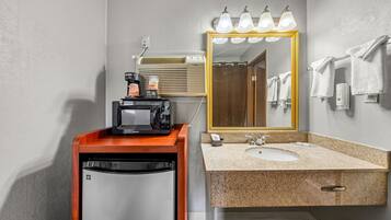 A bathroom with a sink, mirror, towel rack, and a coffee machine.