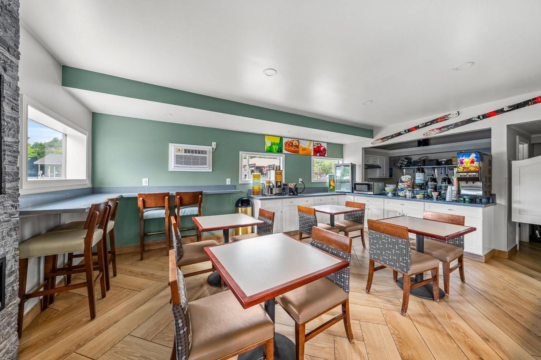 A restaurant with wooden tables and chairs, a kitchen area, and a bar counter.