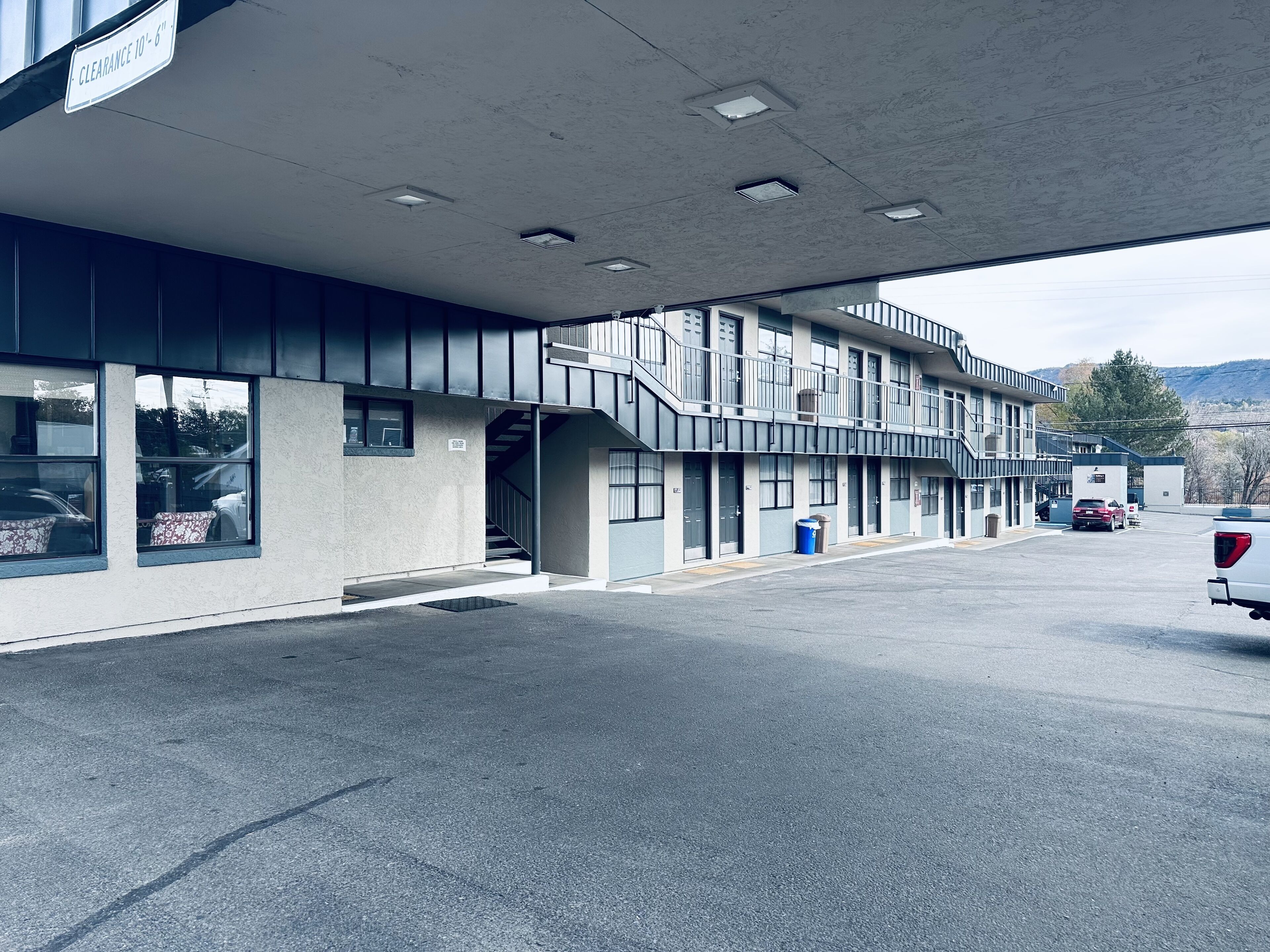 A multi-story building with a flat roof, a covered parking area, and a clear sky.