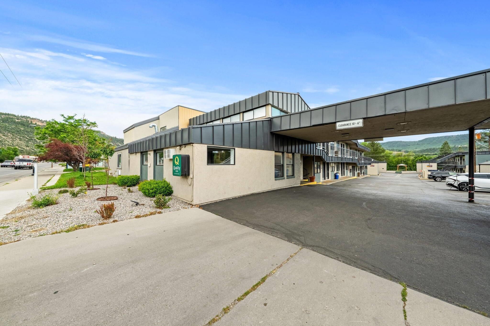 Un bâtiment moderne doté d’une entrée couverte, d’un panneau indiquant que l’on y arrive en 10 minutes en voiture, et d’un espace de stationnement.
