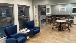 A modern dining area with blue upholstered chairs, a herringbone wood floor, and a stone accent wall.