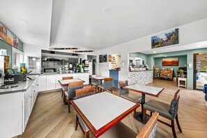 A restaurant with a kitchen area, dining tables, and chairs.