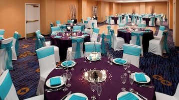A banquet hall with round tables, white chairs, and teal accents.