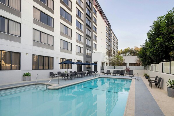 Un hôtel doté d’une piscine, d’un espace extérieur aménagé et d’une façade moderne.