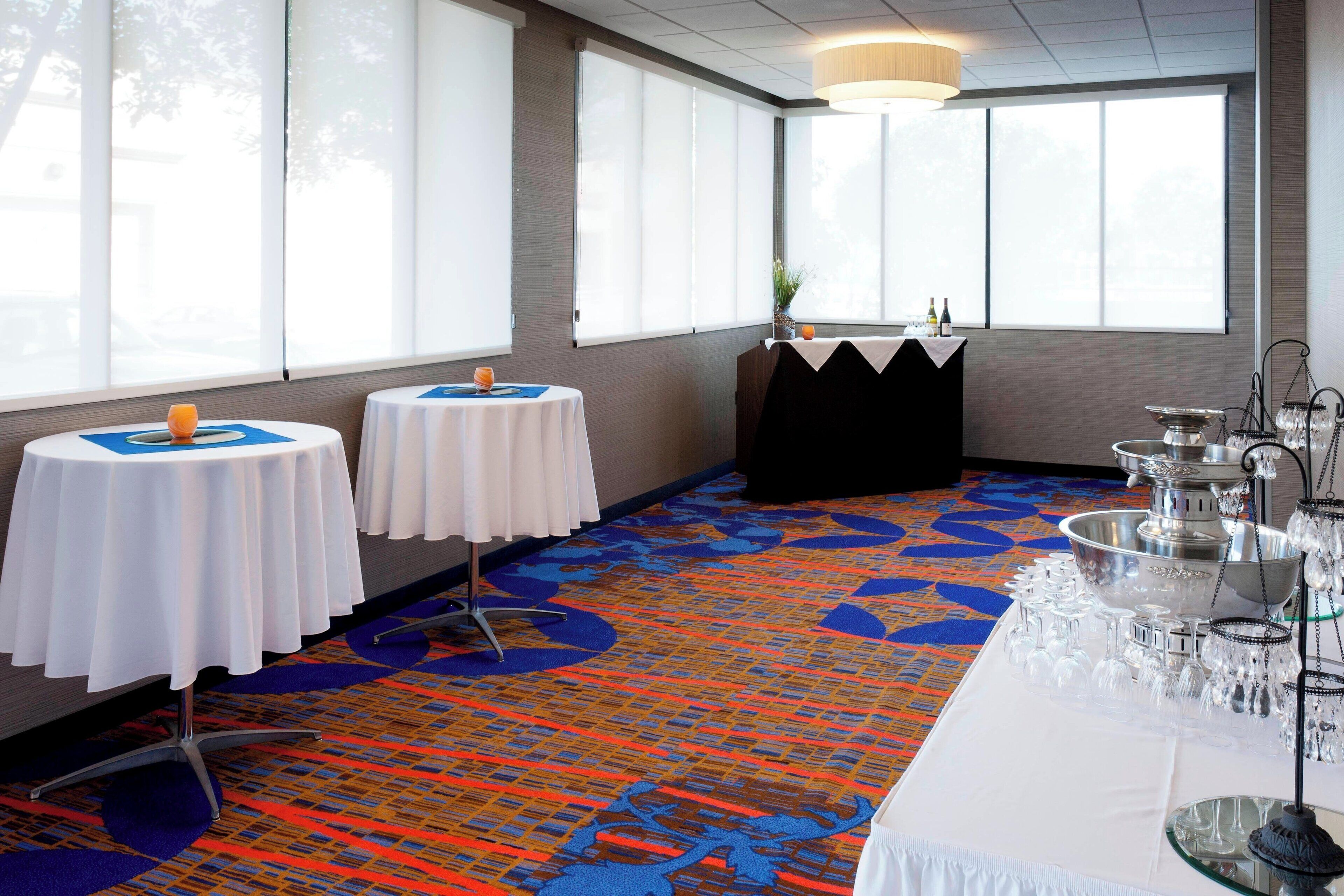 Une chambre d’hôtel avec deux tables rondes, un buffet et une moquette à motifs.