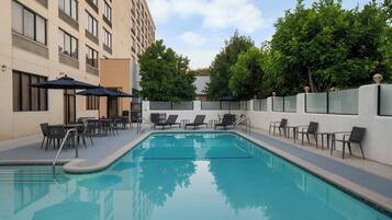 Alberca al aire libre, sombrillas en la alberca y camastros