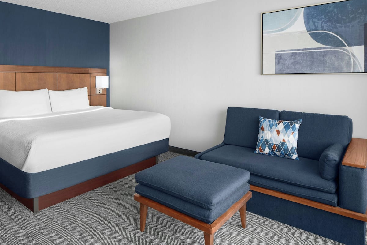 A hotel room with a bed, a sofa, and an ottoman.