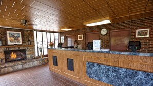A reception area with a stone fireplace, wooden counter, and a clock on the wall.