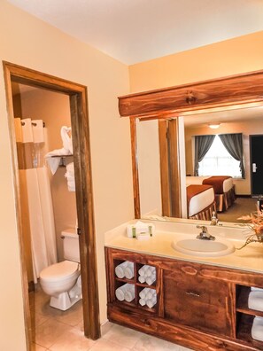 Un baño con tocador de madera, un espejo grande y un inodoro.