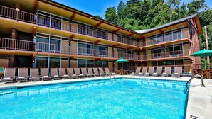 A hotel with a pool, multiple balconies, and outdoor seating.