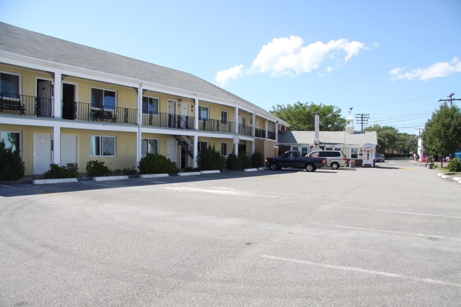 A motel with a two-story structure, a parking lot, and a small adjacent building.