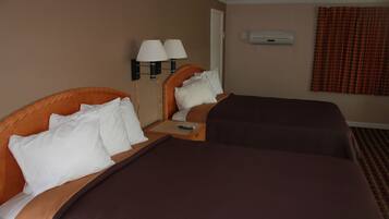 Quarto de hotel com duas camas, cada uma com cabeceira, mesa de cabeceira com controle remoto e ar condicionado fixado na parede.